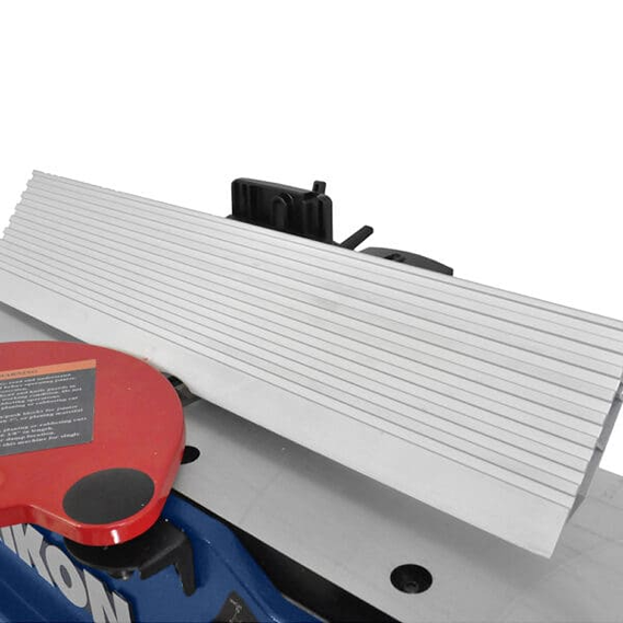 Close-up of an adjustable metallic fence and red cutter head on a benchtop woodworking jointer tool