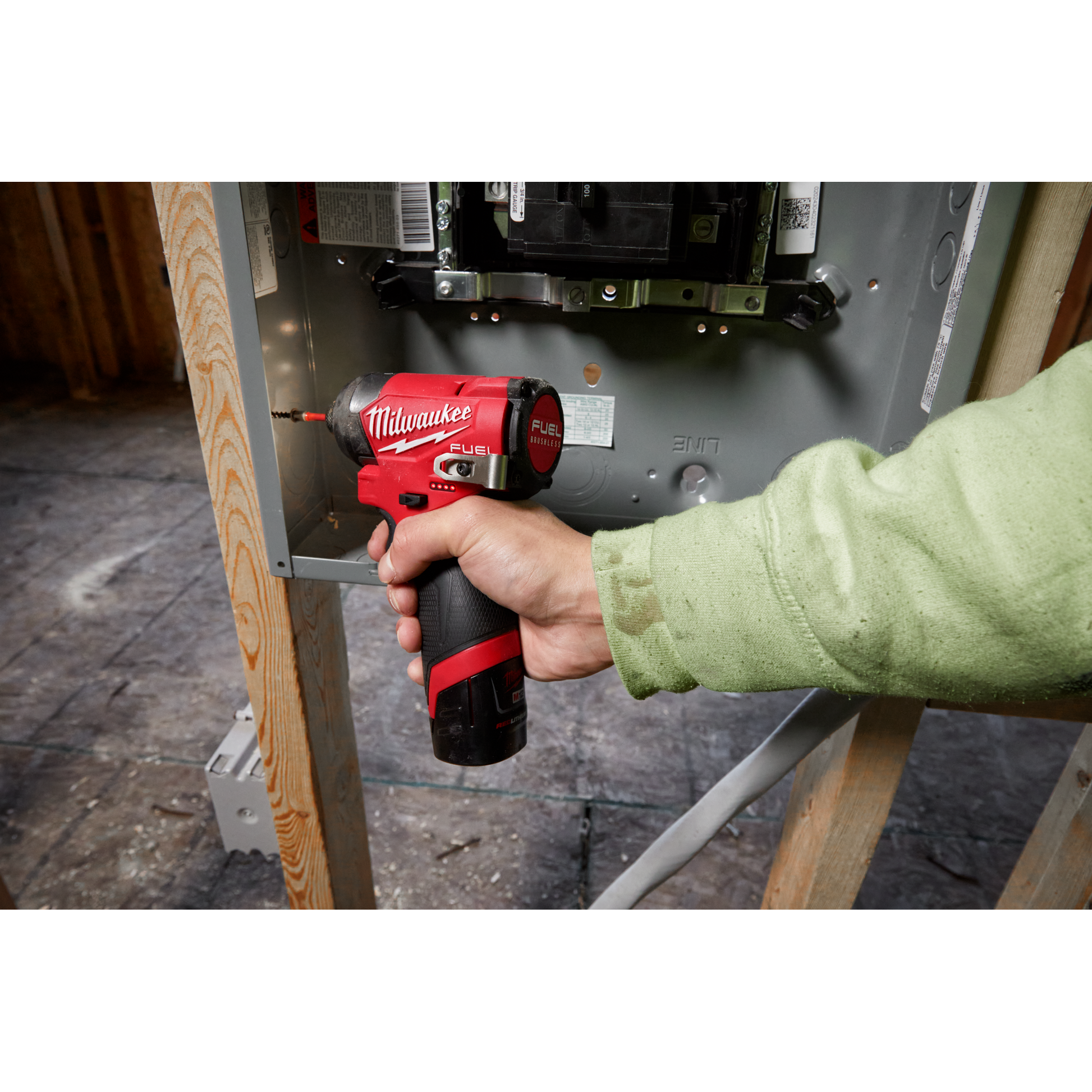 Hand using Milwaukee M12 FUEL impact driver to secure electrical panel in home improvement power tools collection