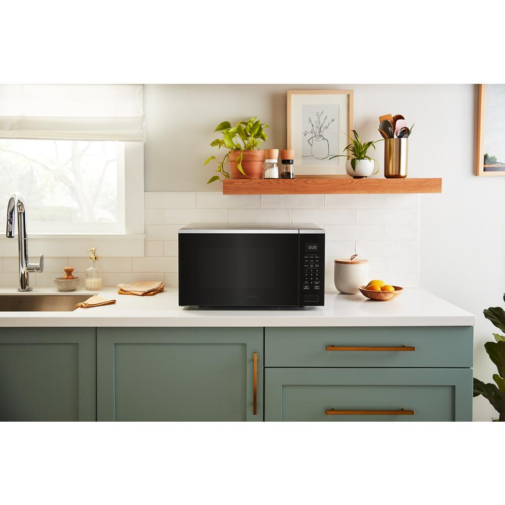 Black sensor cooking microwave with digital controls on white countertop in kitchen and kitchenware setting