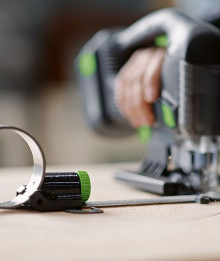 Close-up of a Festool jigsaw equipped with a metal circle cutter accessory for precise circular cuts in woodworking.