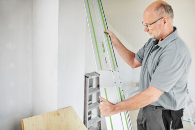 Man using Festool guide rail connectors to join two saw tracks for woodworking and home improvement tools