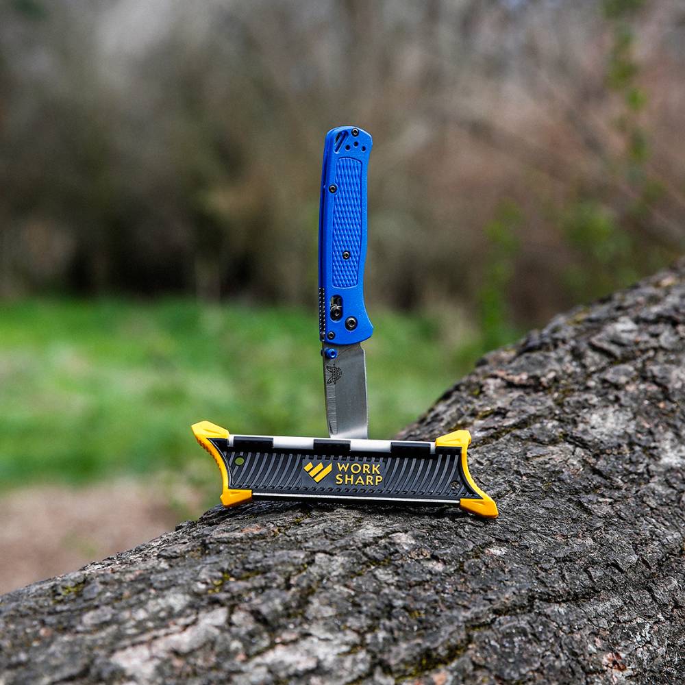 Blue-handled folding knife inserted into a black and yellow sharpener for outdoor woodworking and kitchen tools under $50