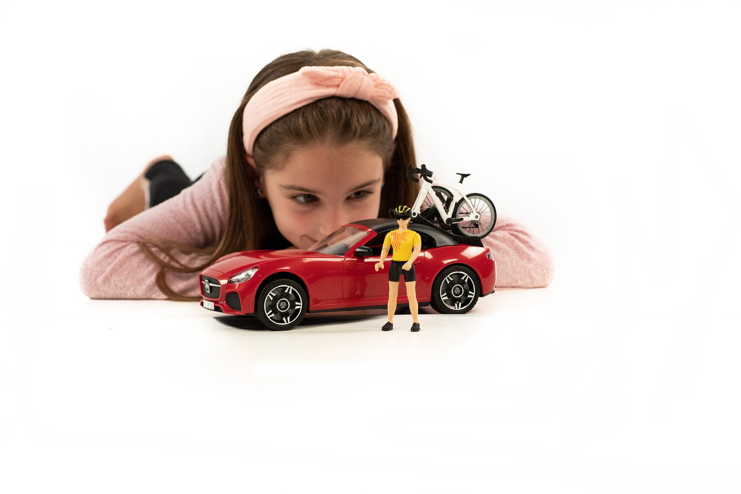 Girl playing with red roadster toy with cyclist figure and white racing bicycle from Bruder Toys under $100 collection