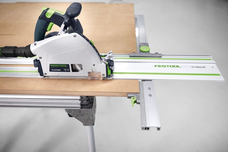 Festool woodworking tool with a parallel side fence accessory on a guide rail cutting a wooden board in a workshop