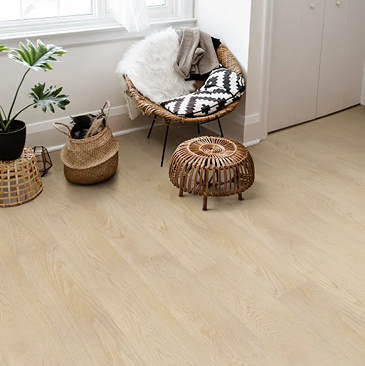 Light khaki vinyl wood flooring with subtle grain texture in a cozy living space featuring wicker furniture and plants