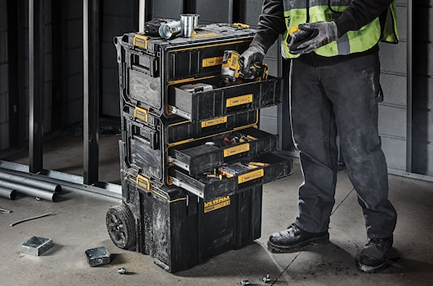 Stacked black and yellow storage system with three drawers open for tool organization on a jobsite environment