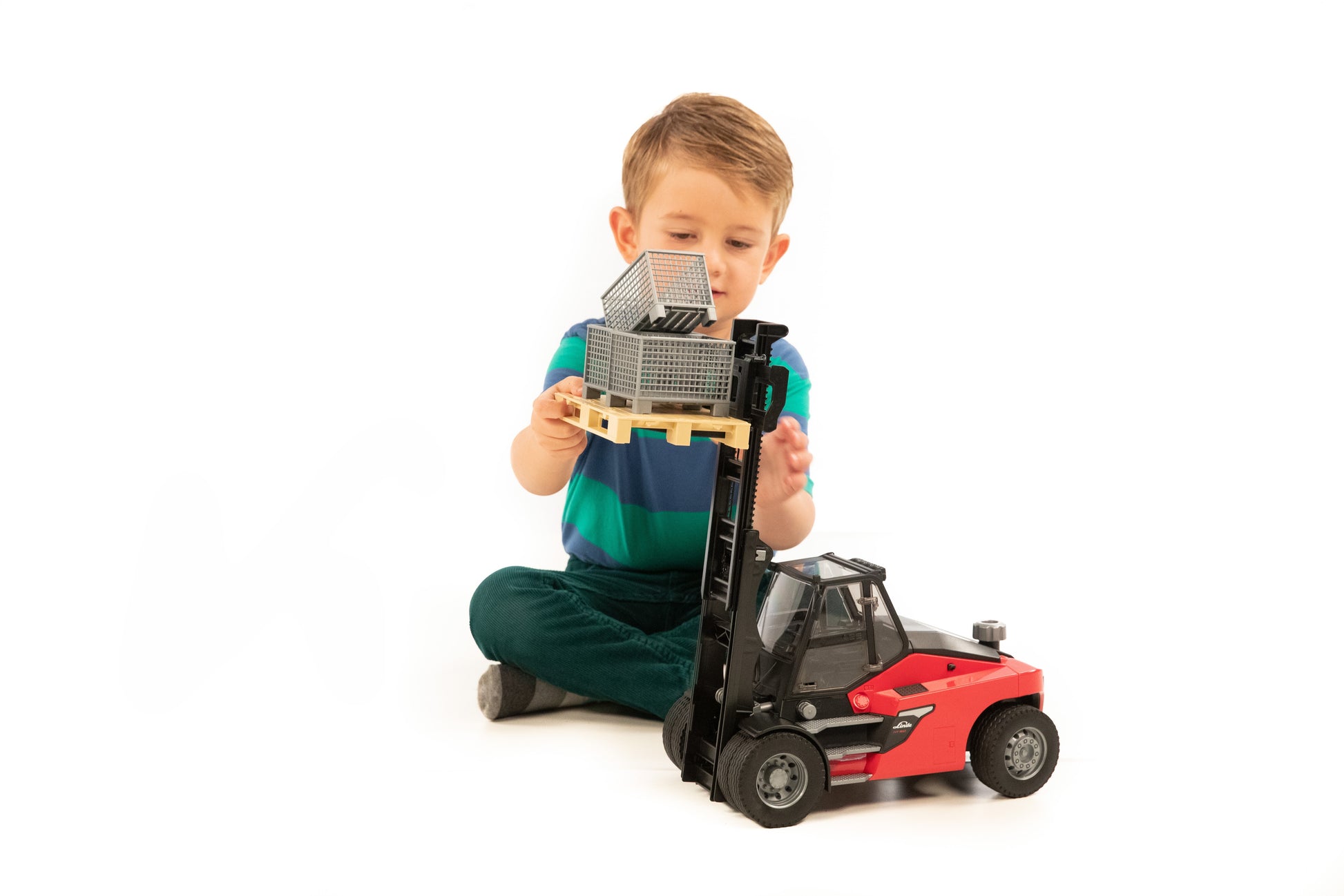 Young boy engaged with a detailed stacker toy lifting a pallet fitted with three gray cages in Toys & Games collection