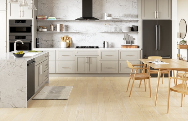 Modern kitchen with black gas cooktop, marble countertops, stainless steel appliances, and light wood flooring