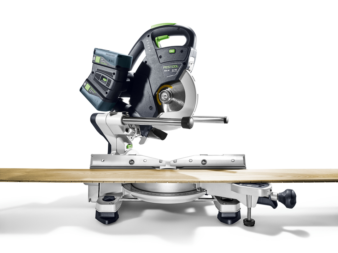 Cordless compound miter saw with battery on a wood plank, suitable for precise woodworking and power tool use