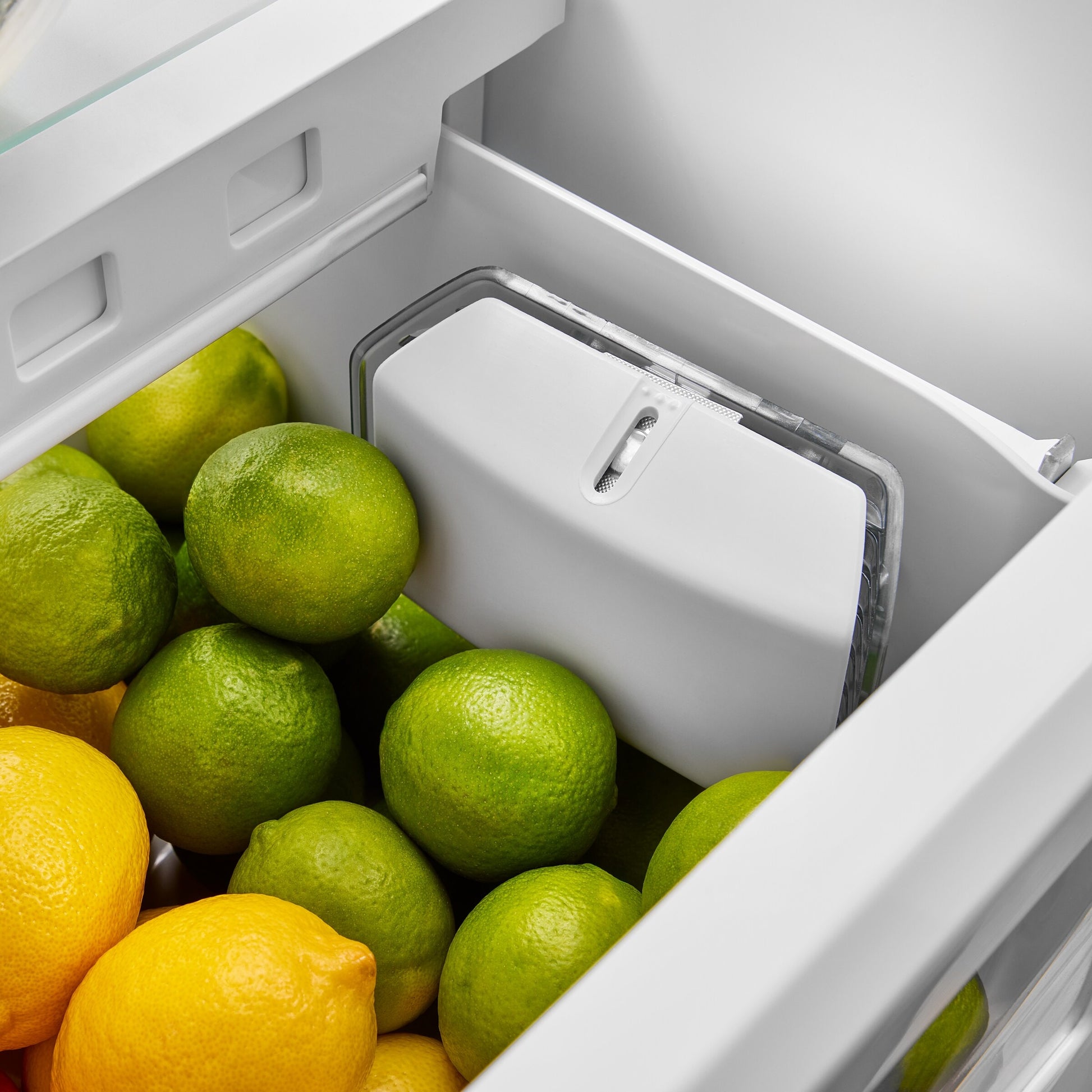 Limes and lemons stored in a crisp, clean refrigerator drawer with humidity control system panel visible
