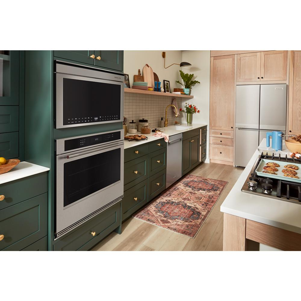 Kitchen with built-in stainless steel convection microwave oven and wall oven featuring green cabinetry and brass hardware