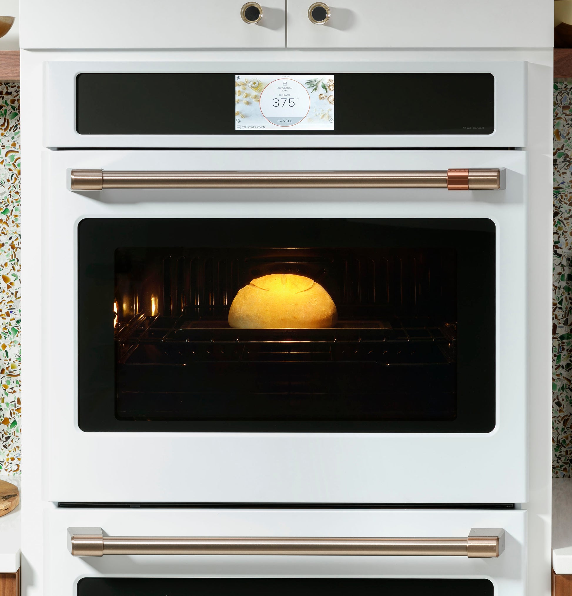 White built-in smart convection oven with digital display showing 375°F and bread baking inside appliance
