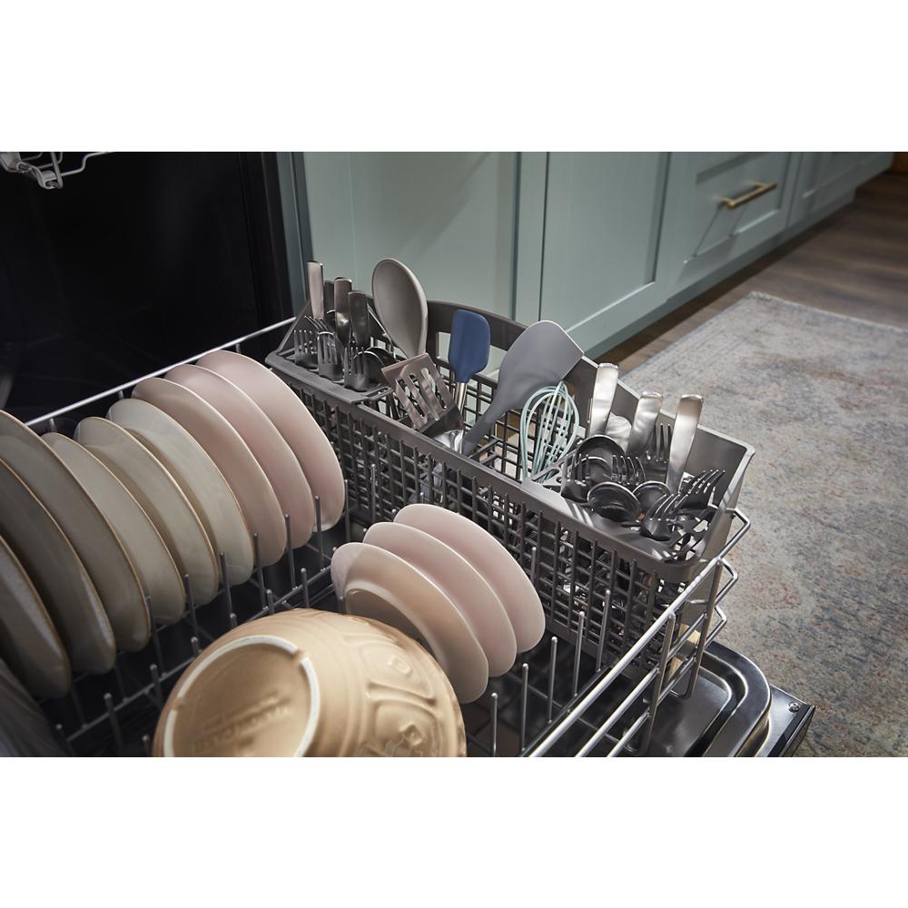 Dishwasher interior loaded with plates and cutlery in water repellent silverware basket on kitchen floor setting