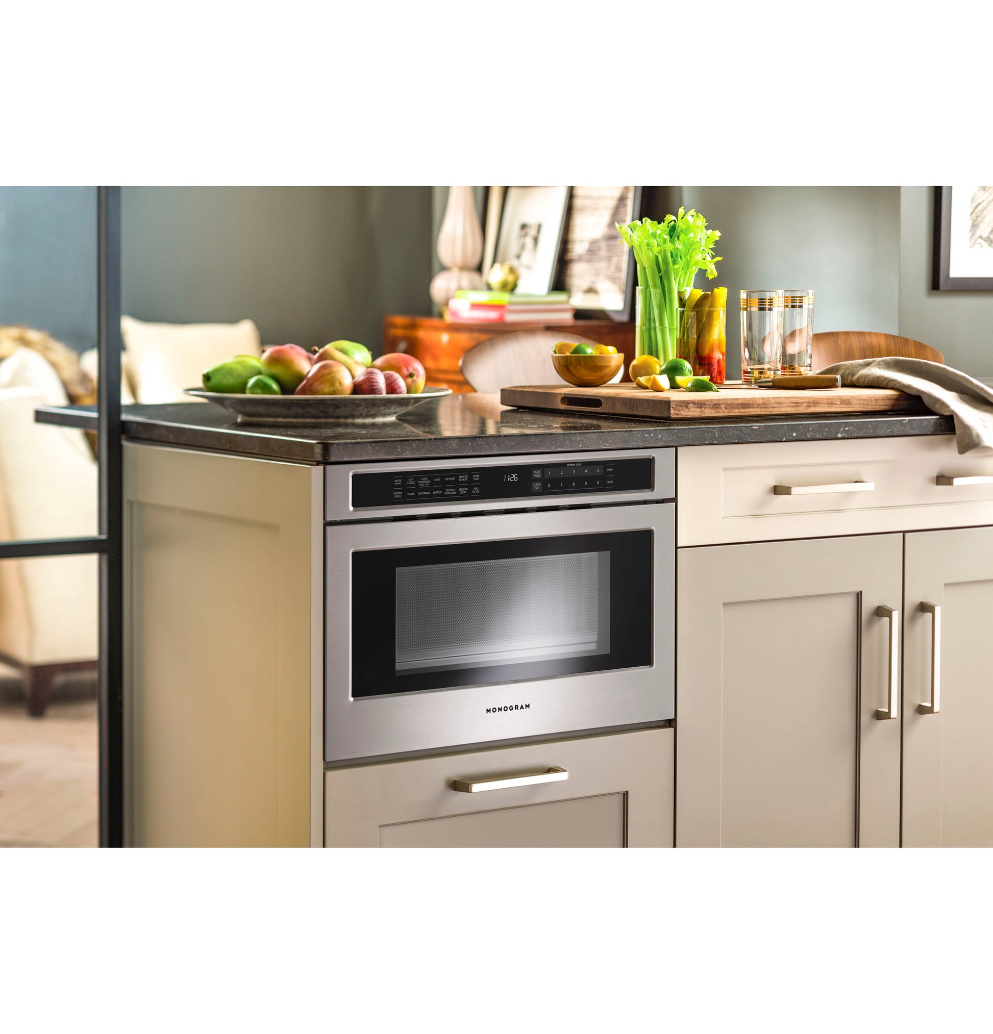 Built-in stainless steel microwave drawer installed in beige kitchen cabinetry with wooden countertop and fresh produce on top