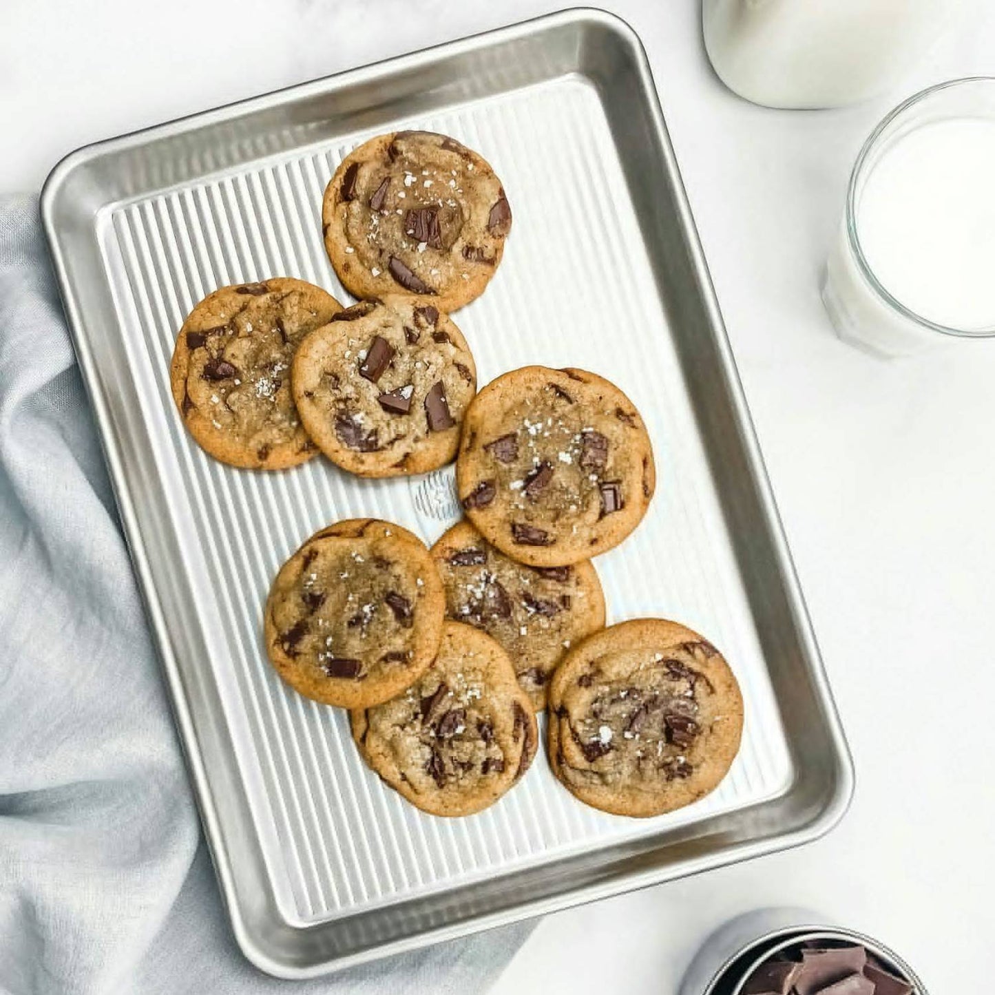 Aluminized quarter sheet pan with ribbed surface holding freshly baked chocolate chunk cookies in kitchenware collection