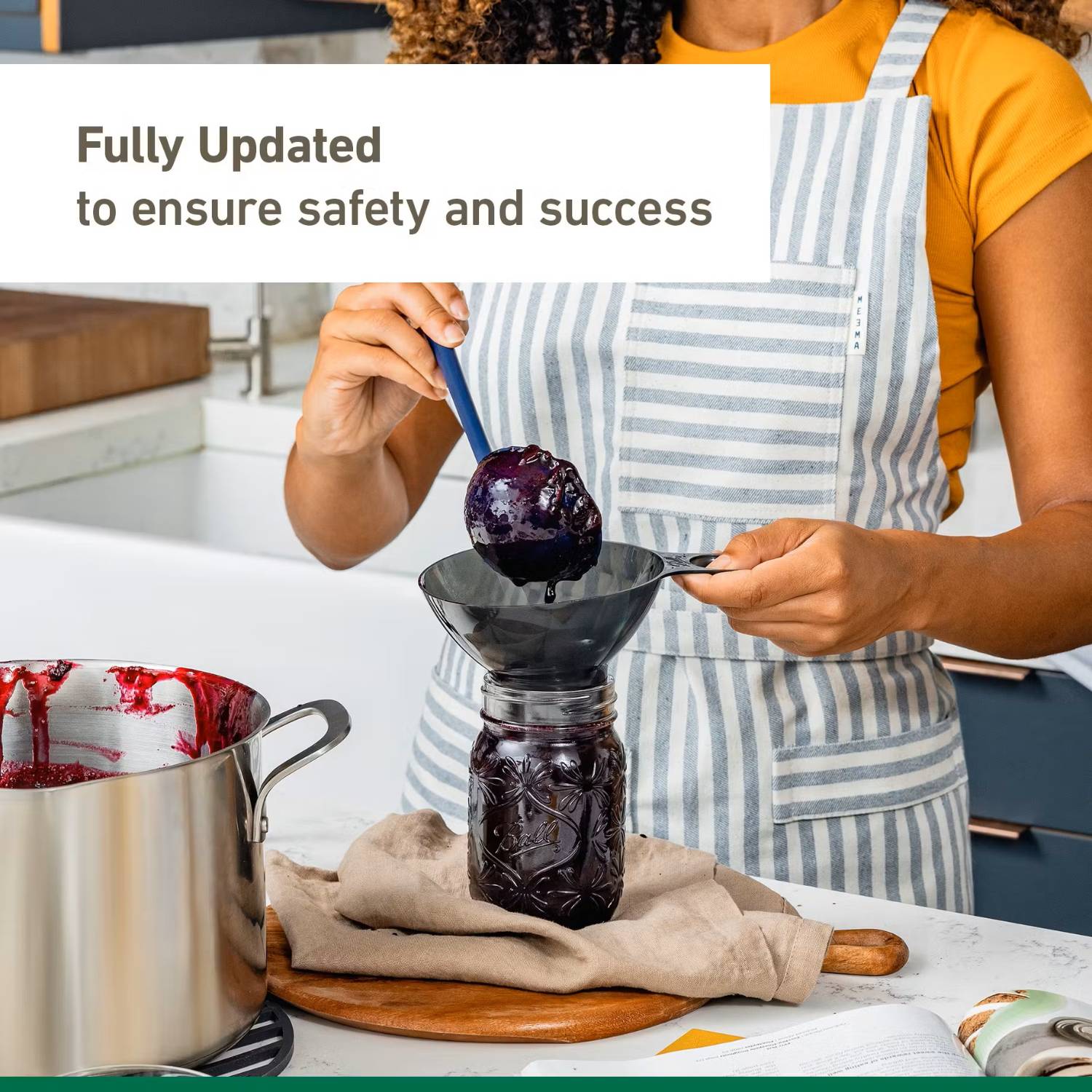 Person wearing striped apron scooping dark jam into glass jar in kitchenware and under $50 collection