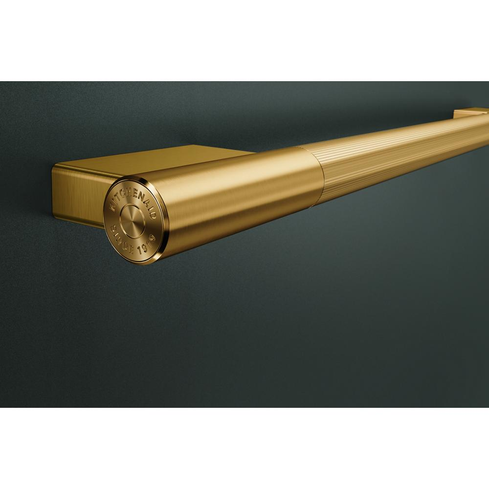 Brushed gold towel bar handle with engraved logo mounted on dark matte surface for luxury kitchenware collection