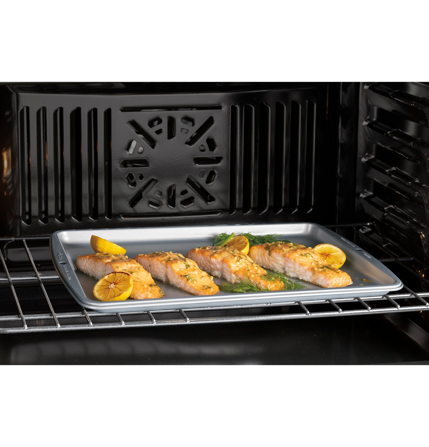 Salmon fillets with lemon and herbs cooking inside a black built-in double wall oven from kitchen appliances collection