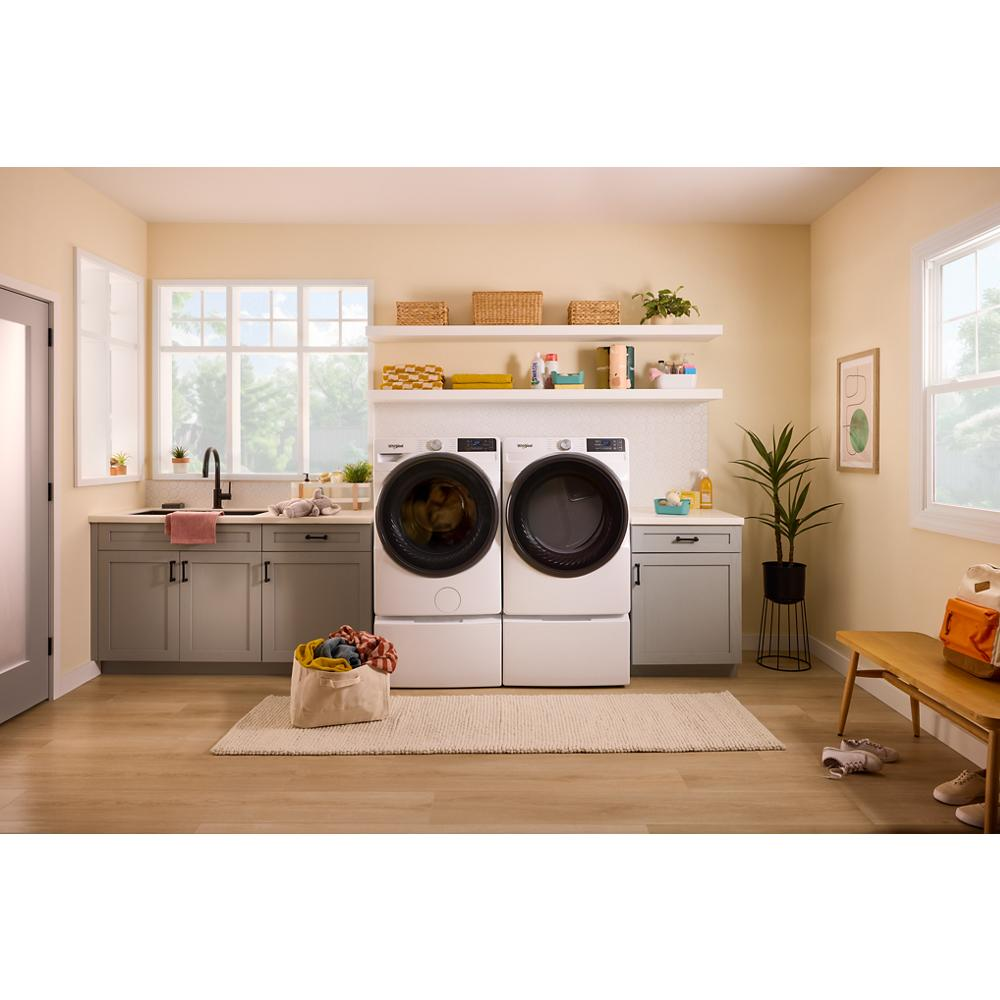 White front load washer and electric dryer set in a bright laundry room with gray cabinets and wooden floor