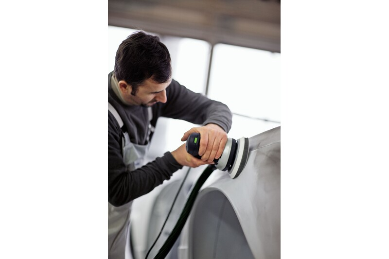 Person using an electric rotary sander with Festool interface backing pad for auto body and home improvement tasks