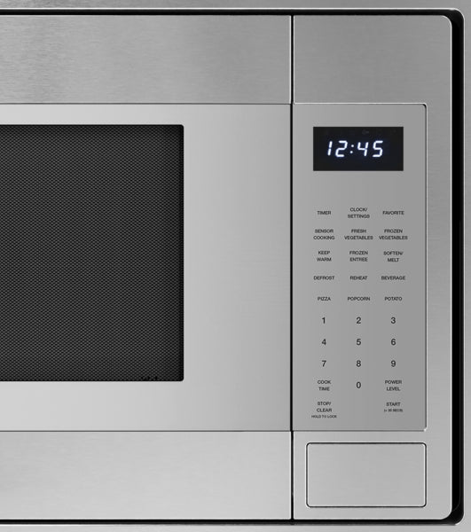 Close-up of stainless steel built-in microwave control panel with digital clock and keypad in modern kitchen setting