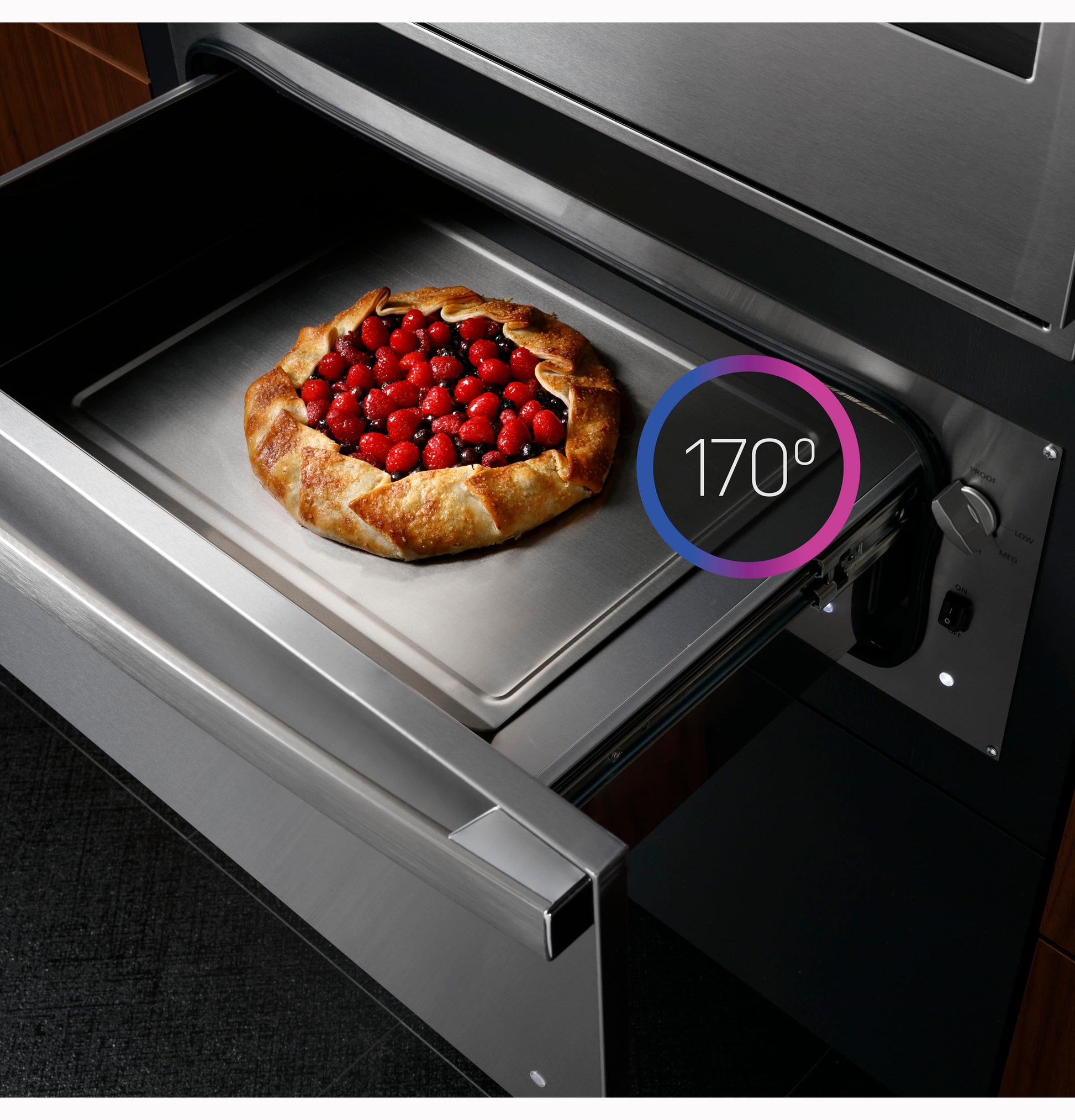 Open warming drawer with a freshly baked rustic berry galette on a baking sheet in modern kitchen appliances setting