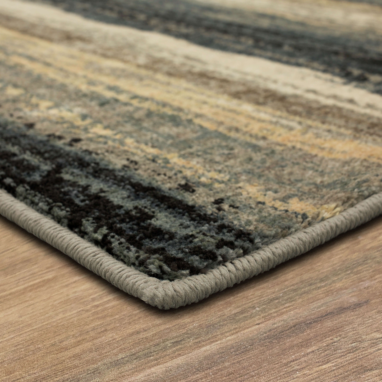 Close-up of textured area rug edge in denim blue, beige, and gray hues on hardwood floor for home improvement