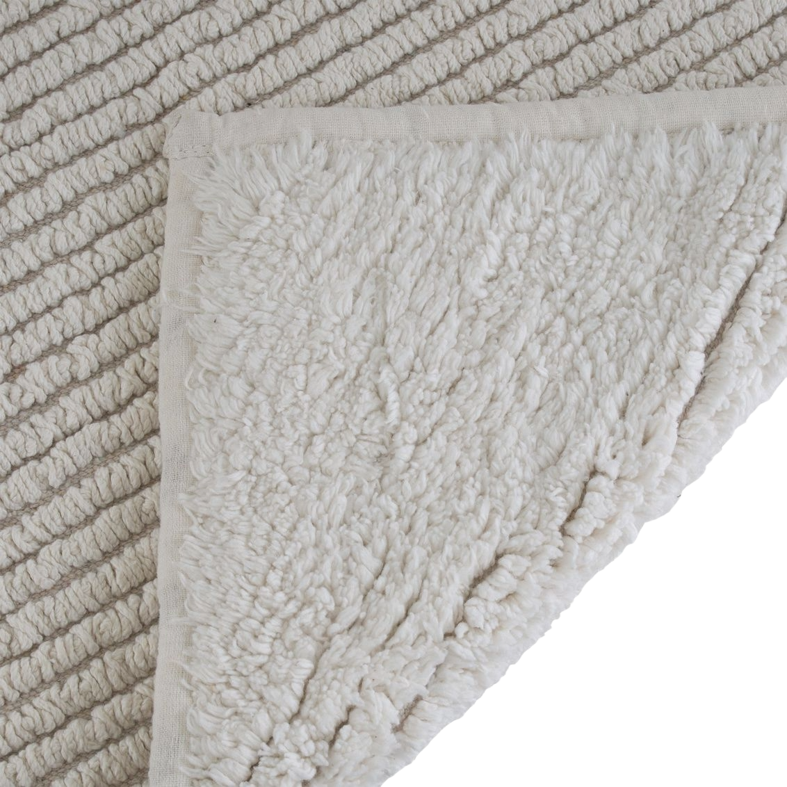 Close-up of plush natural reversible bath mat corner with textured surface for bathroom and home comfort.