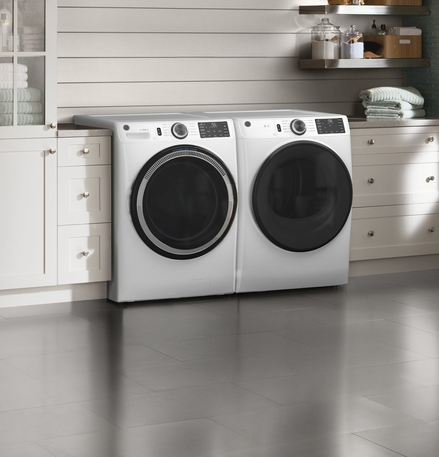 White front load washer and dryer pair with digital controls in a bright, modern laundry room setting