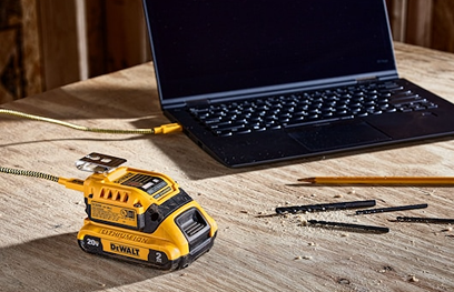 Yellow DEWALT 20V MAX battery charging with USB cable connected to laptop for portable power in tool accessories