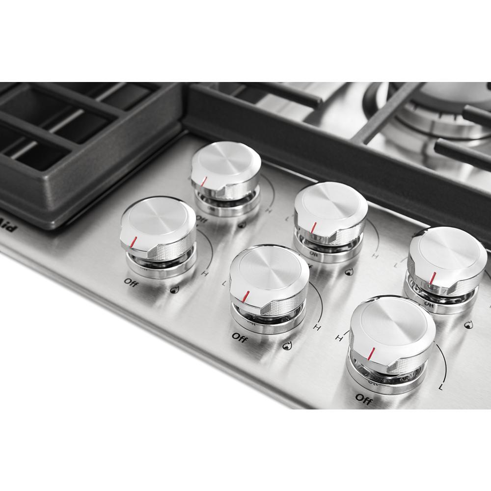 Stainless steel cooktop control panel with six round knobs and continuous cast iron grates from KitchenAid appliances collection