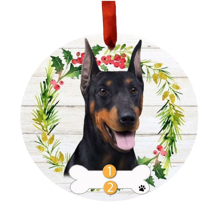 Round Christmas ornament featuring a Doberman dog face with festive holly and greenery wreath and a bone-shaped name tag.