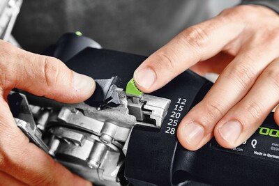 Hands adjusting a green depth setting on a Festool Domino DF 500 Q Plus joiner for woodworking precision
