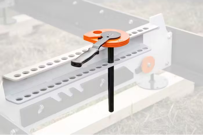 Metal and orange log clamp with mounting bracket for secure wood holding in sawmill tool accessory collections