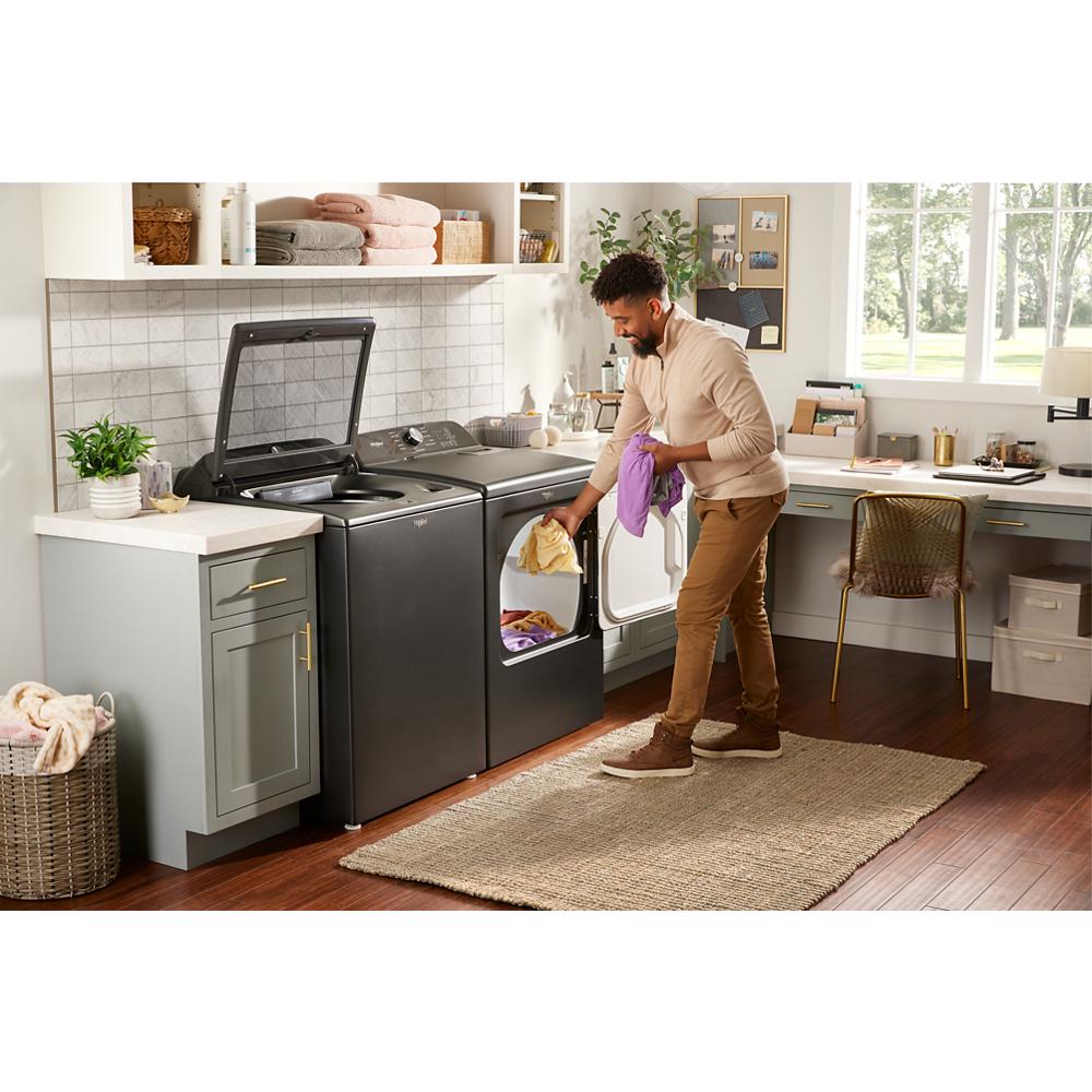 Man loading laundry into black top load washer and matching dryer in stylish home laundry room setting
