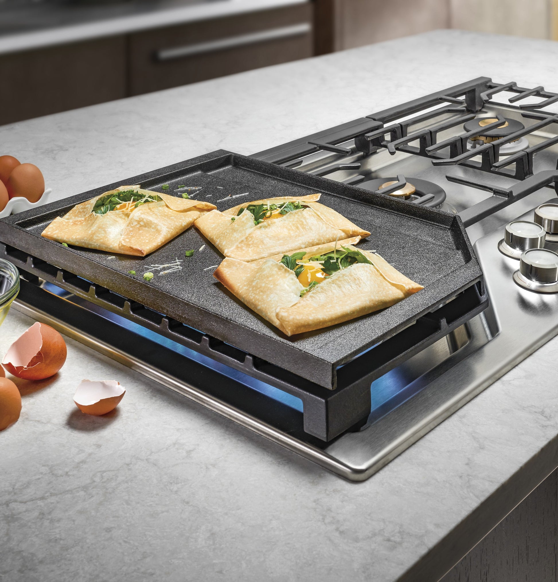 Cast iron griddle on stainless steel gas cooktop with folded crepes cooking, kitchenware and home improvement setting