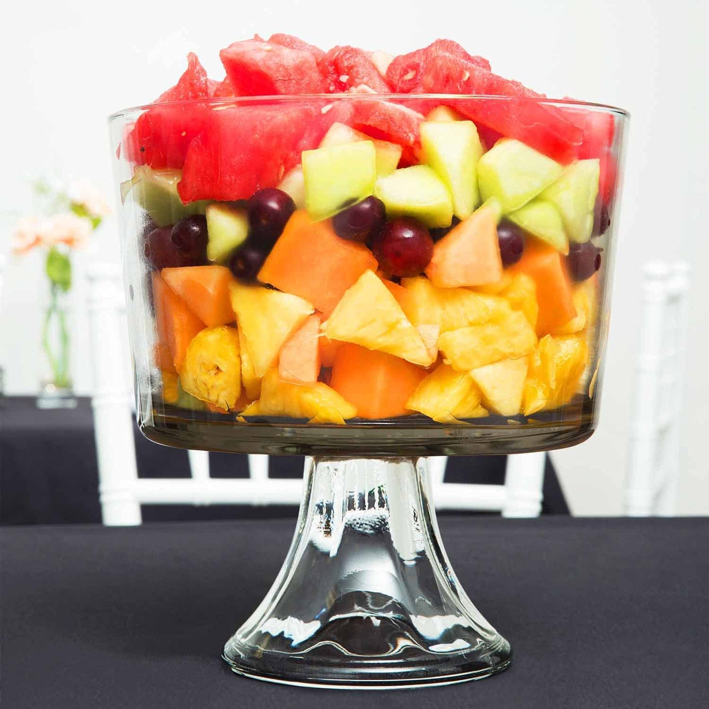 Clear footed glass bowl filled with layered fresh fruit salad, suitable for kitchenware and under $50 collections.