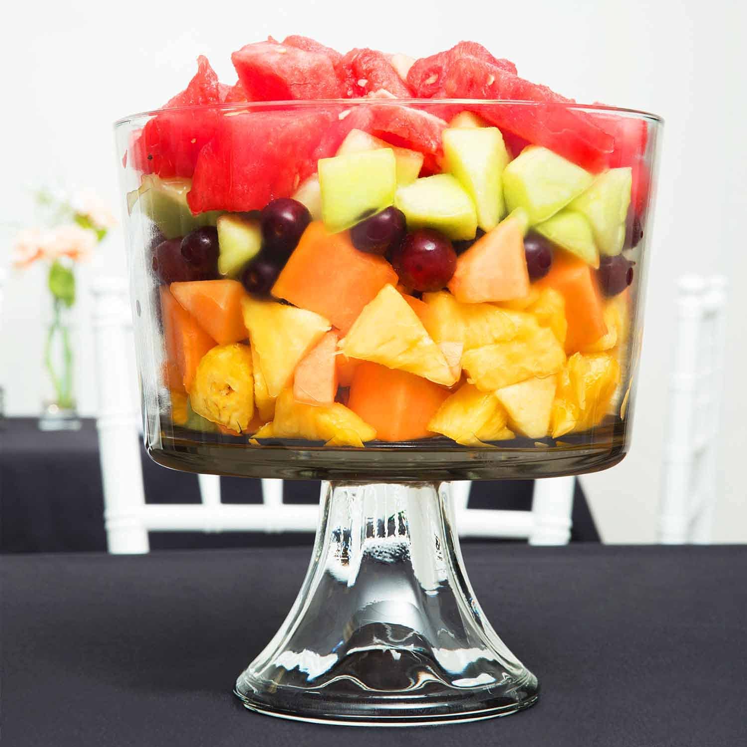 Clear footed glass bowl filled with layered fresh fruit salad, suitable for kitchenware and under $50 collections.