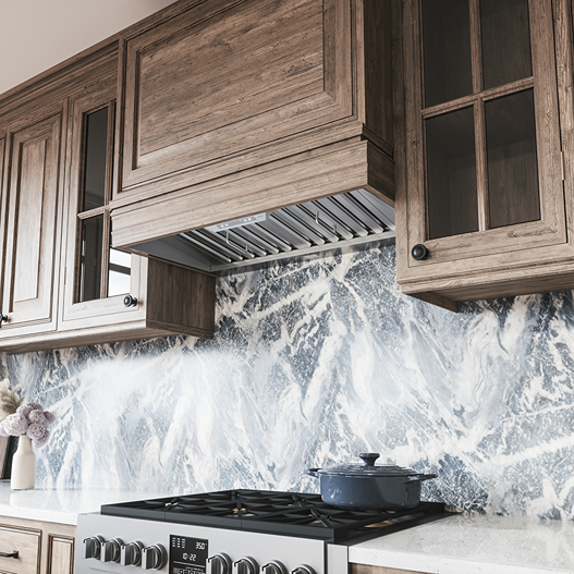 Under-cabinet stainless steel insert hood with baffle filters above a modern gas range in kitchenware collections