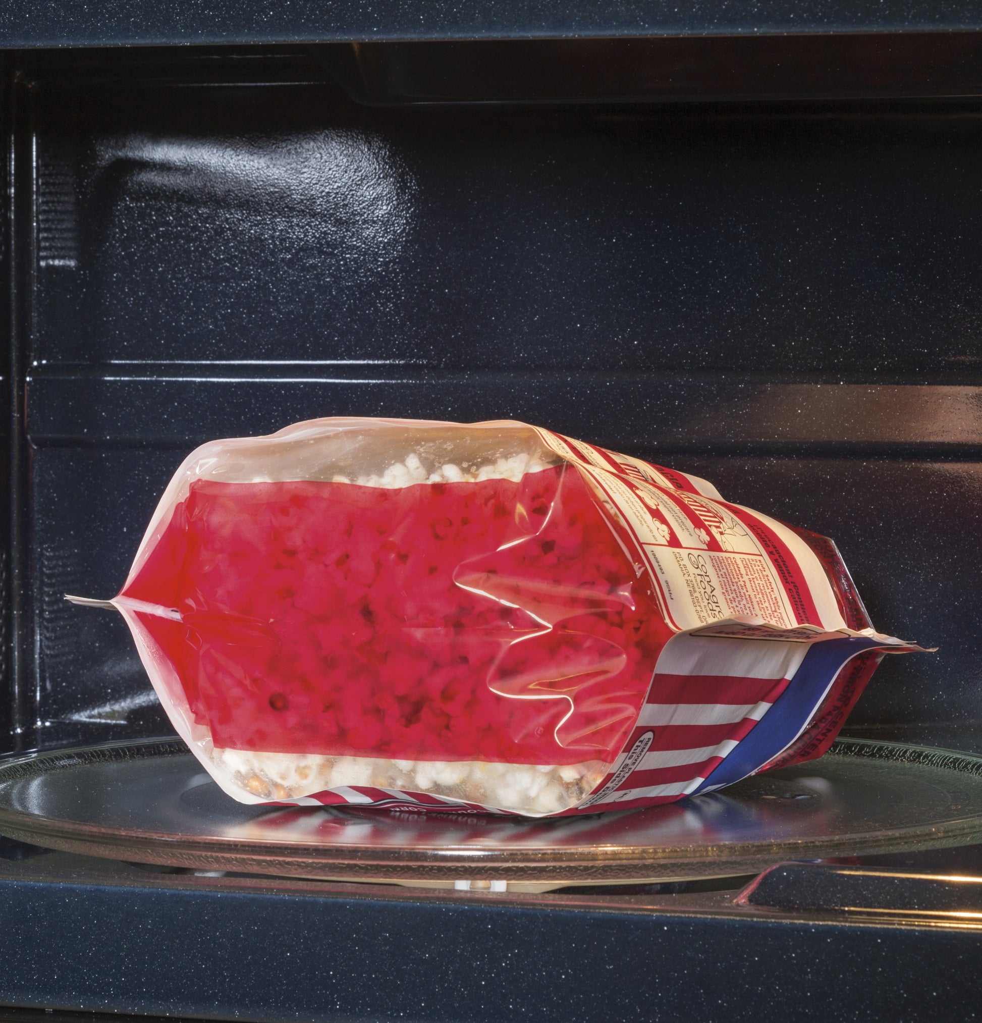 Microwave popcorn bag expanding on glass turntable inside a GE® over-the-range sensor microwave oven from Kitchen & Kitchenware