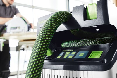 Green and black flexible extractor hose attached to a Festool dust extractor for woodworking tools and home improvement