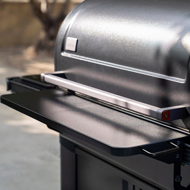 Matte black folding front shelf attached to outdoor grill offering extra workspace for grilling and outdoor living tasks