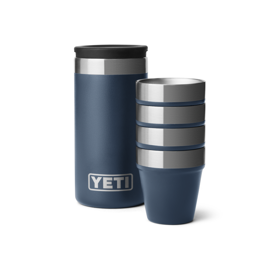 Set of four navy blue stainless steel shot glasses stacked next to matching insulated carrying container in drinkware collection