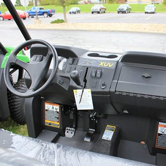Dashboard and steering wheel view of green mid-size utility vehicle with control switches and XUV branding for outdoor use