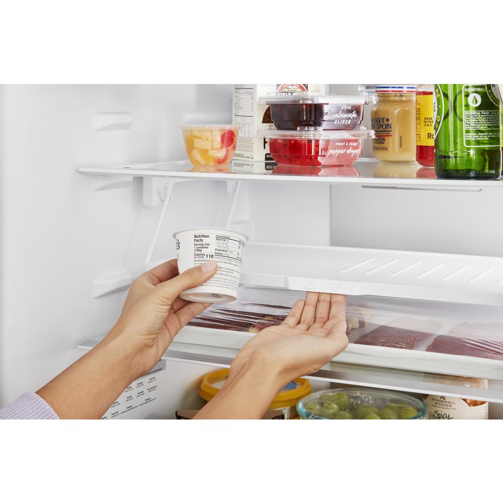 Hands placing a yogurt cup on a shelf inside a garage-ready refrigerator with organized food containers and bottles
