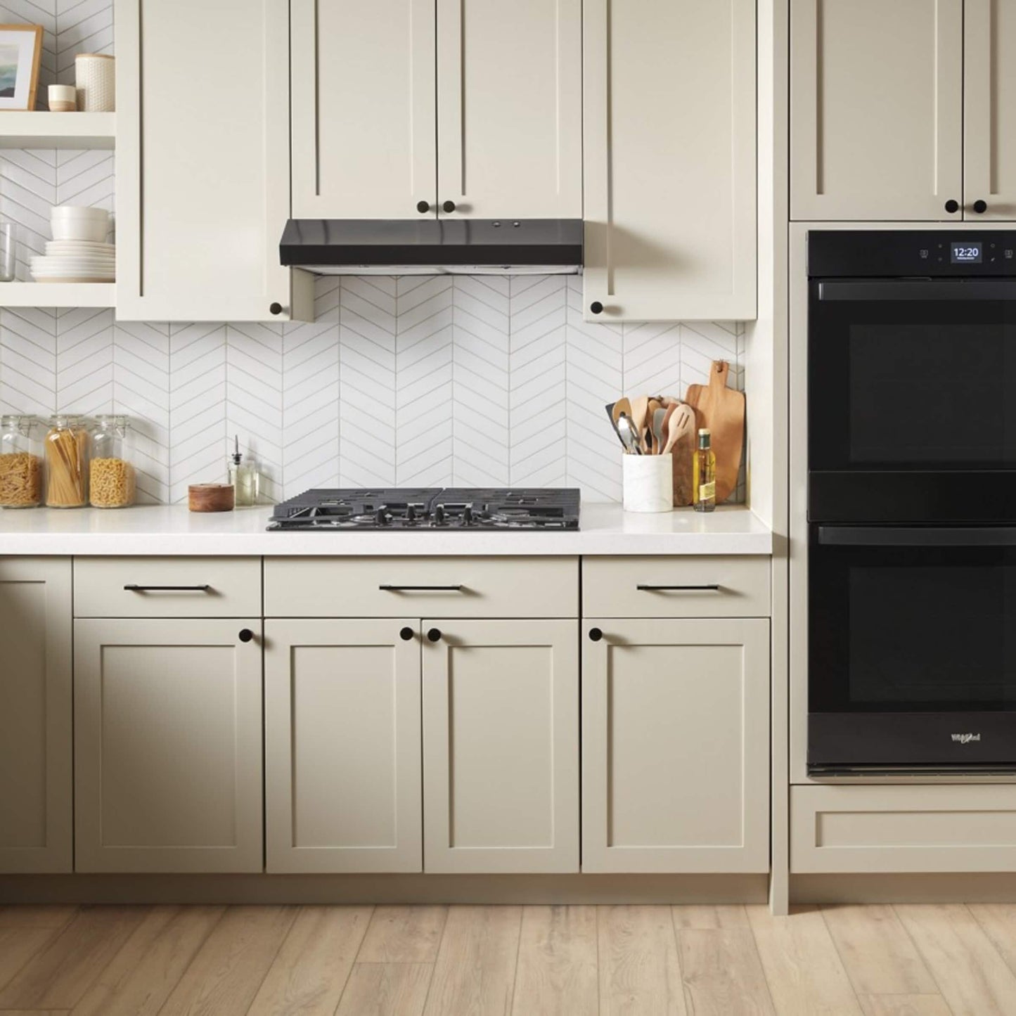 Modern kitchen featuring beige cabinetry, wood floor, gas cooktop, and black double wall oven in appliances collection
