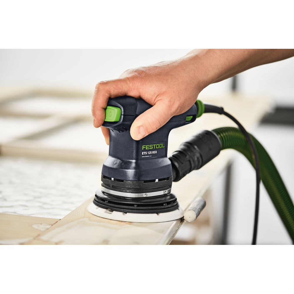 Hand using Festool ETS 125 random orbit sander with dust extractor on wooden frame in woodworking tools setting