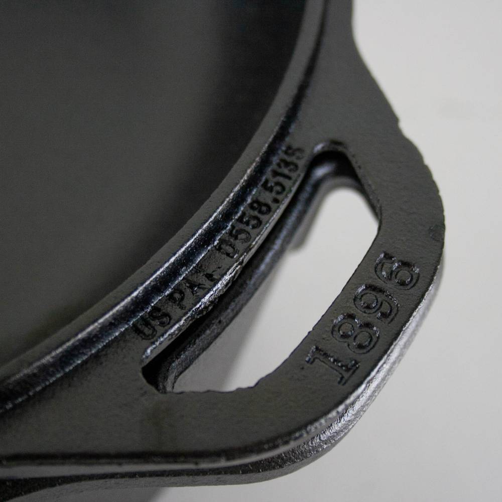 Close-up of black cast iron cookware handle with embossed patent number and model detail in kitchenware collections
