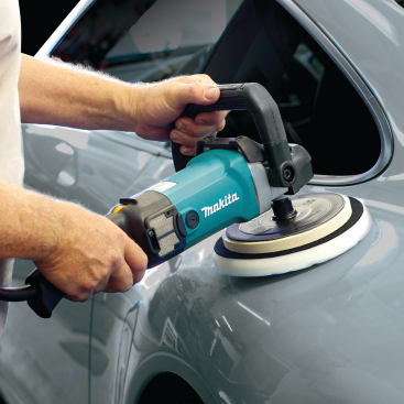Person using teal Makita variable speed polisher with foam pad on silver car for home improvement tasks