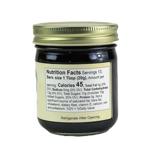 Small glass jar of seedless blackberry preserves with gold metal lid and detailed nutrition facts label visible